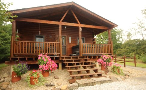 Front of Sky View Cabin with log porch, steps and flower pots in Hocking Hills